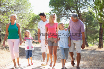 A family, with parents, children and grandparents, walk through park