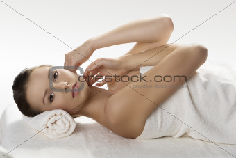 pretty girl lying on a table with towel with hands near the face