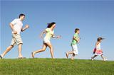 Young family, parents with children,  running through field