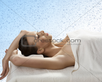 pretty girl lying on a table with towel with arms behind the hea