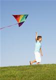 Young boy runs with kite through field