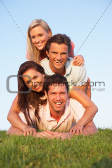 Two, young couples posing on a field