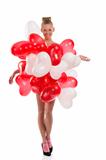 blonde girl with many balloons on her body looks in to the lens