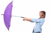 Young woman struggling with a purple umbrella on a windy day