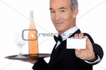 waiter carrying bottle of wine with glass and showing his personal card