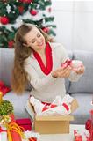 Happy young woman packing Christmas present parcel