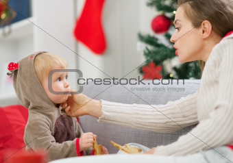 Mother cleaning eat smeared baby eating Christmas cookies