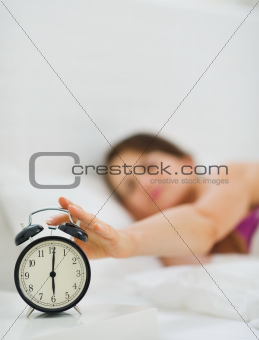 Closeup on female hand reaching to turn off alarm clock