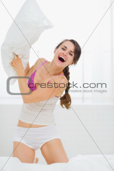 Happy young woman pillow fighting