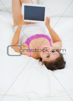 Happy young woman laying on bed with tablet PC