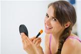 Smiling young woman applying makeup