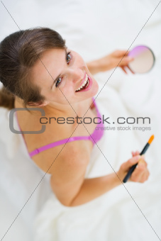 Smiling young woman applying makeup. Upper view