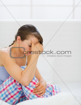 Stressed young woman sitting on bed