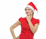Portrait of thinking young woman in Santa hat looking on copy space