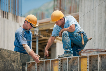 Two construction workers installing concrete formwork frames
