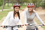 Two Female friends riding bikes in park