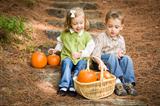 Cute Young Brother and Sister Children Sitting on Wood Steps Laughing with Pumpkins in a Basket.