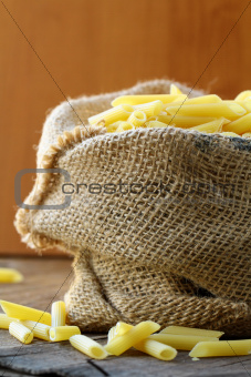 Linen bag of pasta (penne) on a wooden table