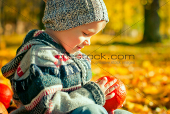 cute little boy playing with pumpkin in the park