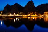 Mountain Silhouettes and Illuminated Town of Omis Reflecting in 