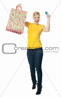 Excited teenager holding shopping bag and card