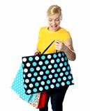 Young girl looking excitedly inside her shopping bag