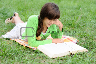 Girl reading a book lying on the grass
