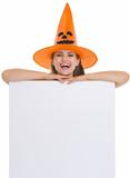 Smiling woman in Halloween hat with blank billboard
