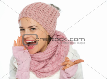 Happy young woman in knit winter clothing pointing on copy space