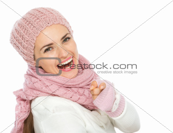 Happy woman in knit winter clothing pointing in camera