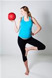 Pregnant woman exercising with exercise ball while balancing