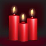 Three red burning candles on black background.