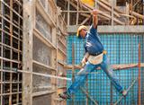 Construction worker balancing between scaffold and formwork fram