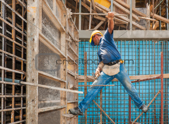 Construction worker balancing between scaffold and formwork fram