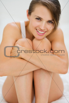 Happy young woman sitting on bed