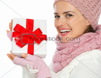 Smiling woman in knit winter clothing holding Christmas present box