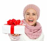 Happy woman in knit winter clothing giving Christmas present box