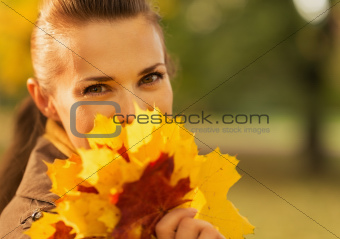 Happy woman hiding behind bunch of fallen leaves
