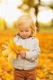 Baby holding fallen leaves