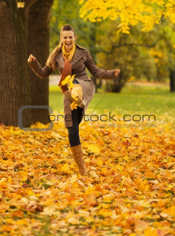 Cheerful woman kicking fallen leaves
