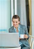 Business woman drinking coffee and looking in laptop