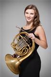 young female musician with concert french horn in black dress
