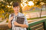 Outdoor Portrait of a Pretty Mixed Race Female Student Holding Books on a Sunny Afternoon.