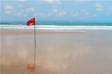 Red flag on beach with no swimming notes.