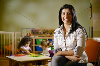 happy teacher with children eating in kindergarten
