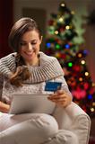 Happy woman with tablet PC and credit card in front of Christmas tree