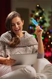 Happy woman in front of Christmas tree making online purchases