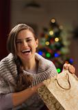 Smiling woman with shopping bag in front of Christmas tree