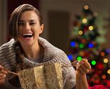 Happy woman with shopping bag in front of Christmas tree