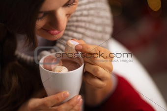 Closeup on woman taking out marshmallow from cup of hot chocolate